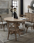 Round hardwood dining table with bleached finish, black iron pedestal base, and warm brown tones for elegant gatherings. by Sostter at brixbailey.com