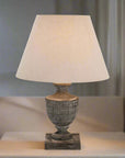 a bold wooden table lamp with a grey-wash patina and soft linen shade in dramatic lighting