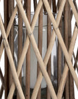 Handwoven wicker lantern with intricate rattan weave, casting warm light patterns, perfect for indoor or outdoor decor. by sostter at brixbailey.com