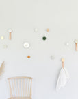 playful white sand ceramic and beech wood hook on a bright yellow wall