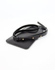 playful black leather crossbody phone bag with gold buttons, worn over a denim jacket