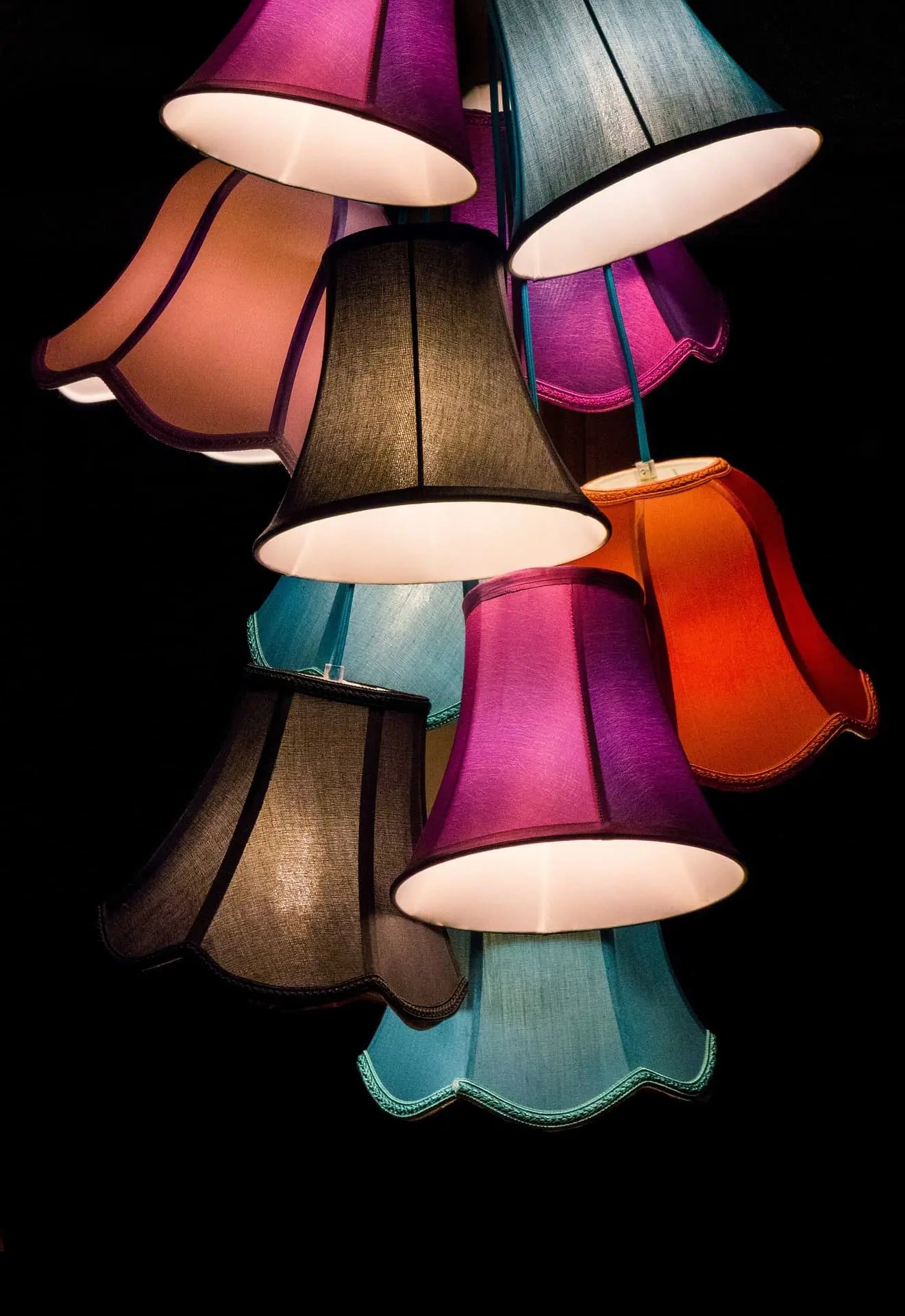 Cluster of colourful hanging lampshades in jewel tones on a black background — featured in the Brix + Bailey home décor collection