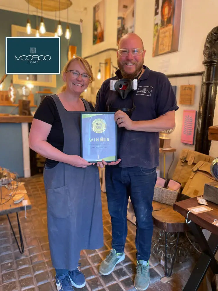 The founders of Mooboo Home smiling in their lighting workshop, showcasing handcrafted, purpose-driven designs stocked at Brix + Bailey.