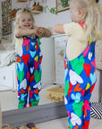 Premium Toby Tiger kids denim overall with multicolor heart print, adjustable straps, snap buttons, soft organic cotton, stylish blue pinafore for toddlers by Toby Tiger at brixbailey.com
