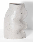 a soft white ceramic vase with gentle flowing curves, lit by morning light in a cozy home setting