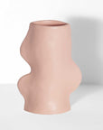 soft pink ceramic fluxo vase on a cozy tabletop, its flowing curves glowing in warm morning light