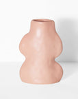 playful pink ceramic vase with flowing lines on a bright windowsill, casting a fun shadow