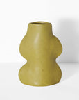 small pistachio ceramic vase on a tabletop holding a single dried flower stem