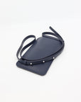 playful navy blue leather crossbody phone bag with a fun, energetic vibe on a sunny day