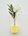 bold yellow ribble wall vase made of beech wood hanging solo on a clean white wall