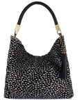 Large black spot cow print leather grab bag by Sostter with tassel and crossbody strap at www.brixbailey.com