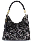 Large black spot cow print leather grab bag by Sostter with tassel and crossbody strap at www.brixbailey.com