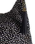 Large black spot cow print leather grab bag by Sostter with tassel and crossbody strap at www.brixbailey.com