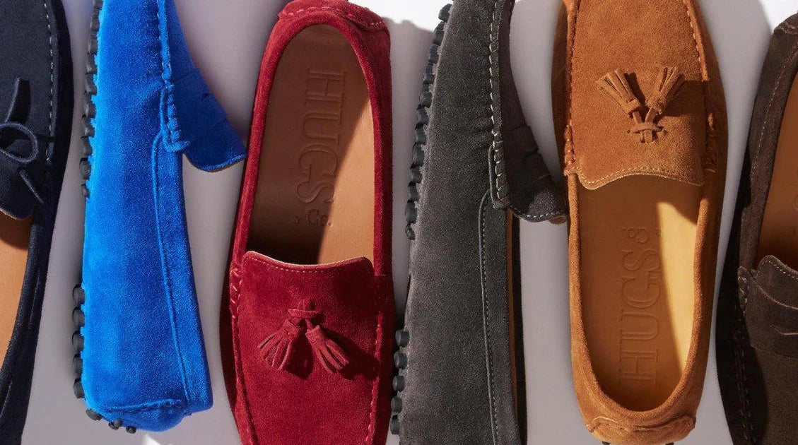 A row of Hugs & Co suede driving shoes in navy, blue, red, grey and tan, laid flat and overlapping