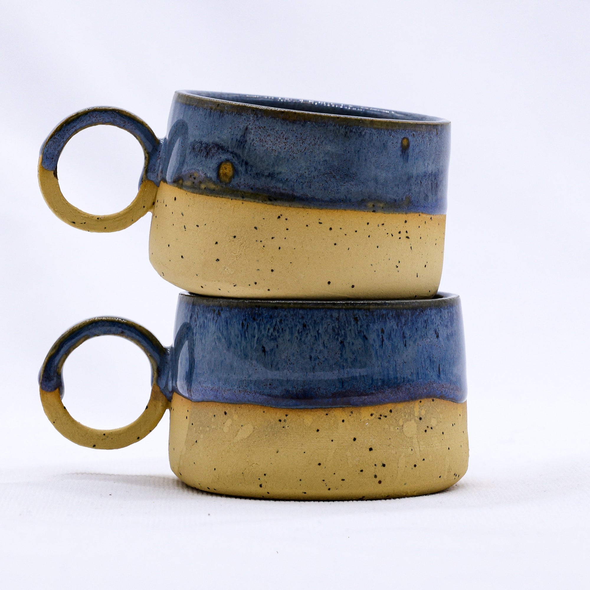 Ribera handmade stoneware mugs and bowls in earthy matte glazes, grouped on a wooden table