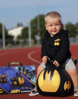 confident toddler riding a vibrant batmobile hopper toy indoors