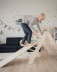 boy using a handmade climbing frame in wood wearing  a striped top from Brix + Bailey. 