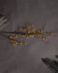 a soft-focus close-up of vibrant yellow forsythia blossoms on a realistic artificial stem