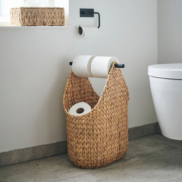 Luxury handwoven water hyacinth toilet paper holder, stylish modern bathroom storage with wooden handle, natural woven basket design by Ella James at brixbailey.com