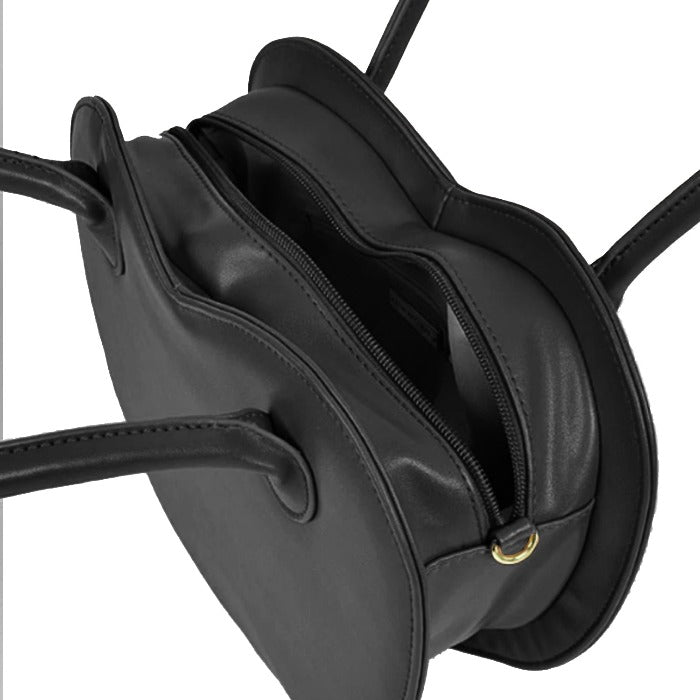 soft black leather shoulder bag with heart motif, gold hardware, and cozy warm lighting