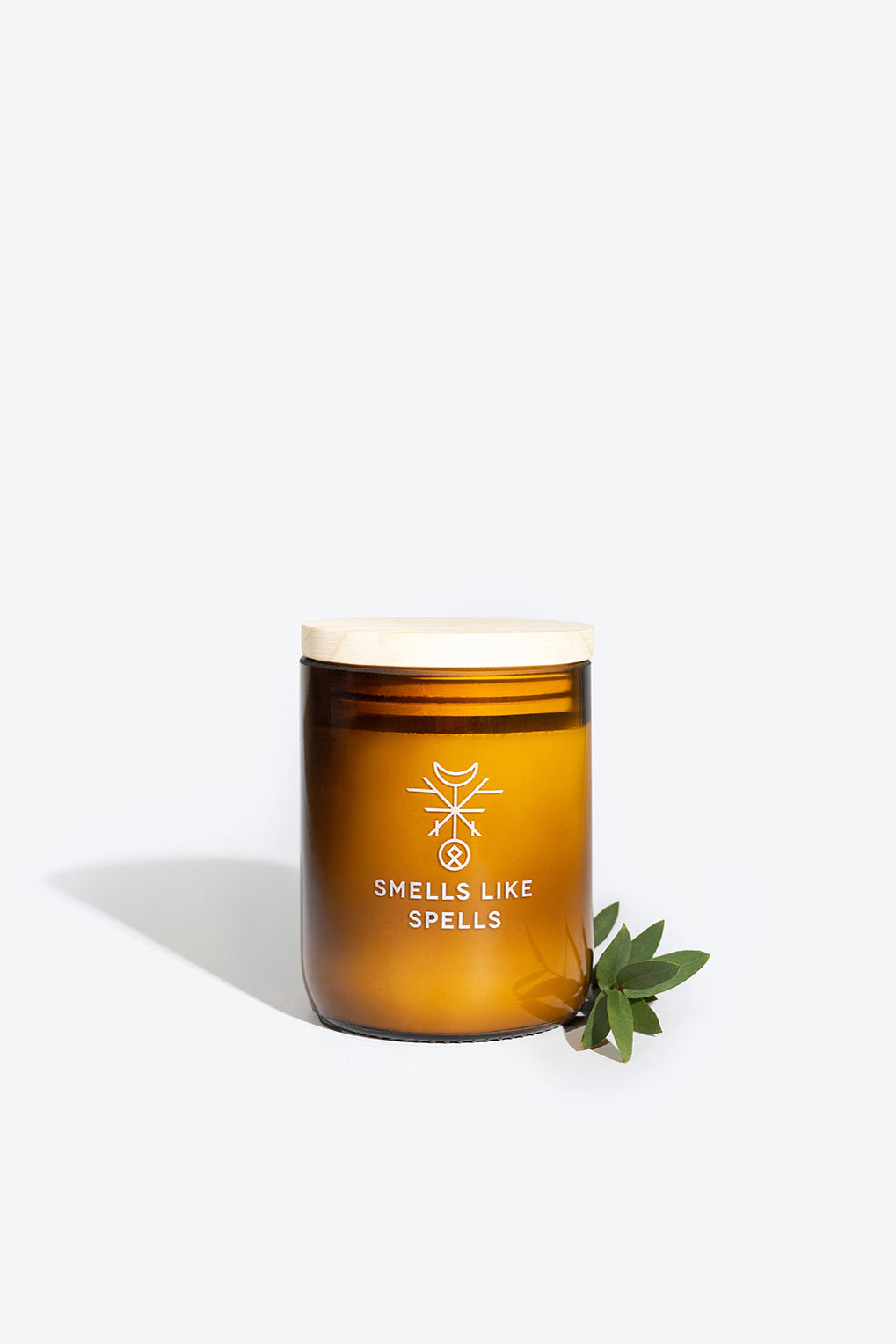 a softly glowing odin scented candle in amber glass, radiating a comforting sandalwood and juniper aroma