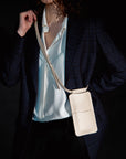 beige leather crossbody phone bag with gold buttons in bold studio light