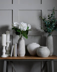 Minimalist white ceramic vase with sculptural silhouette, perfect for floral arrangements in modern decor. by sostter at brixbailey.com