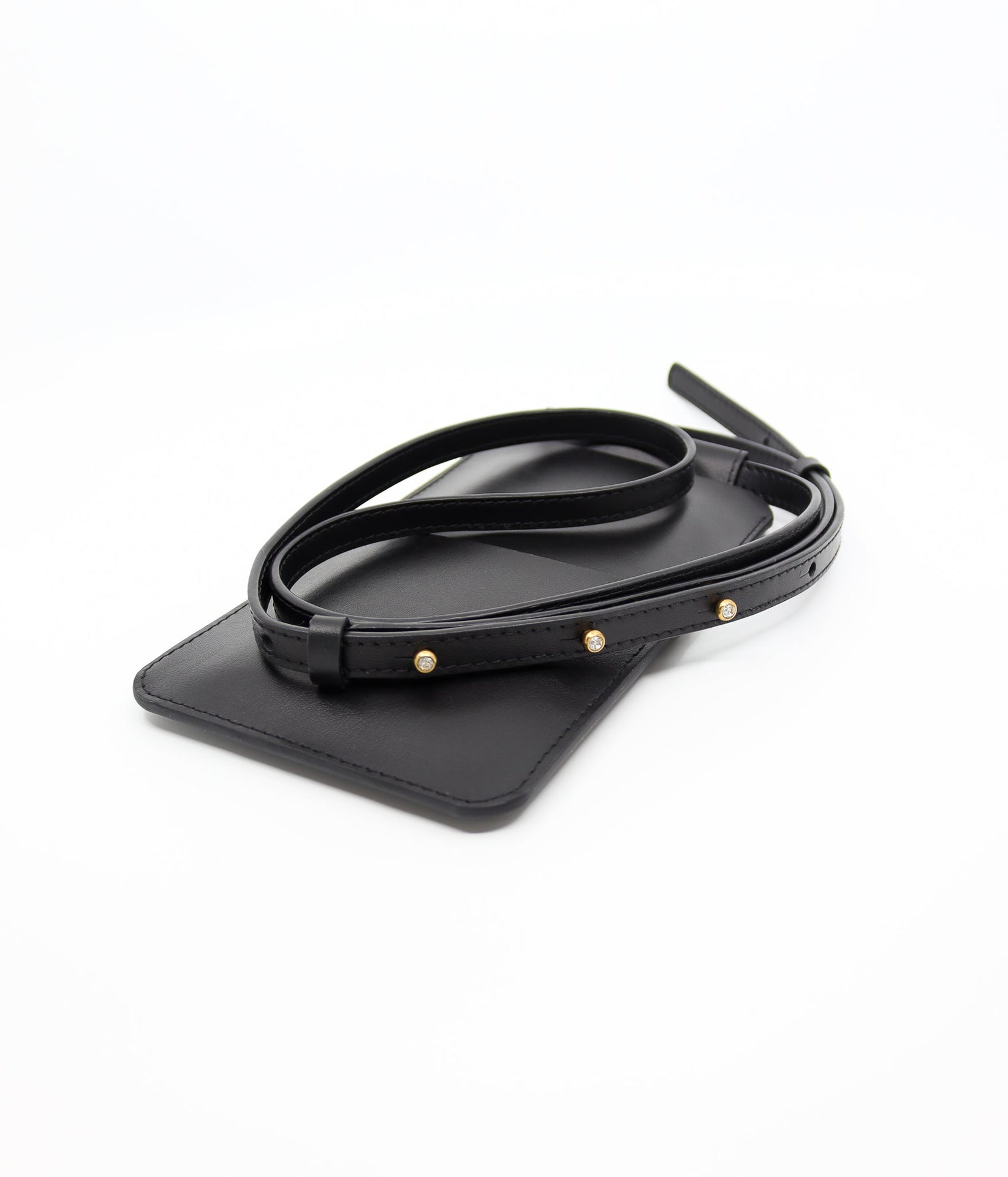 playful black leather crossbody phone bag with gold buttons, worn over a denim jacket