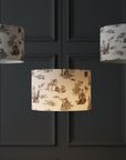 Three Brix + Bailey urban toile lampshades hanging at different heights against dark charcoal panelling, the centre one lit