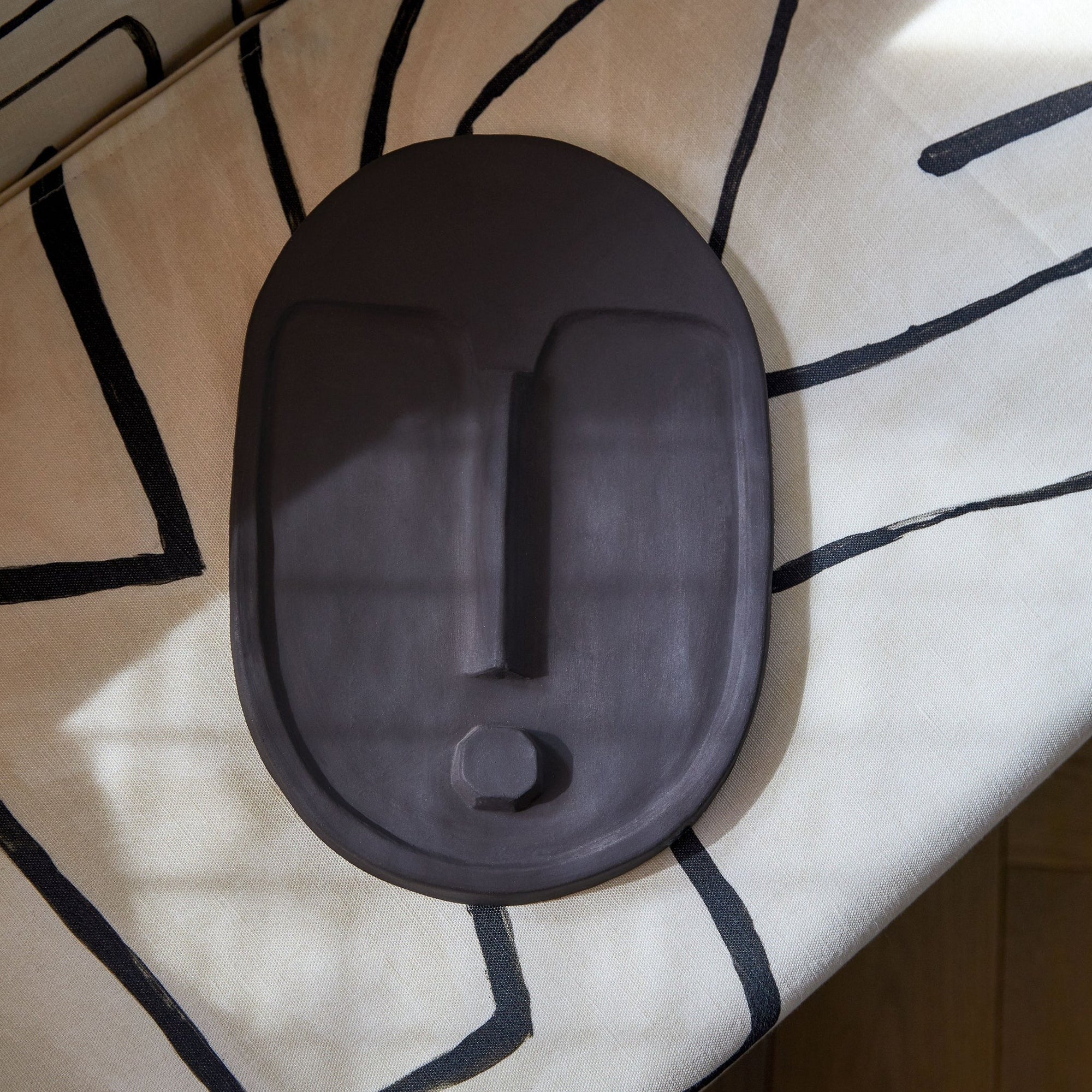 bold abstract ceramic wall mask in anthracite grey with a striking matte terracotta glaze