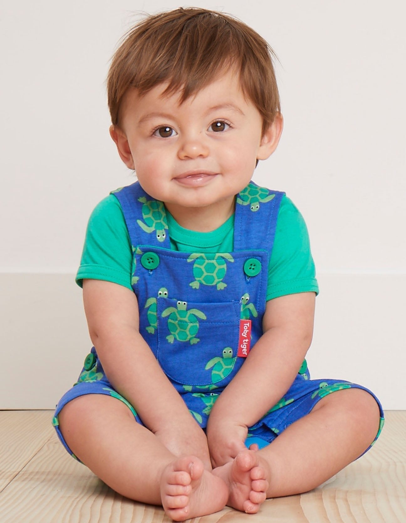 Premium green and blue turtle print overalls, adjustable straps, snap buttons, soft GOTS certified organic cotton, stylish kids summer romper by Toby Tiger at brixbailey.com