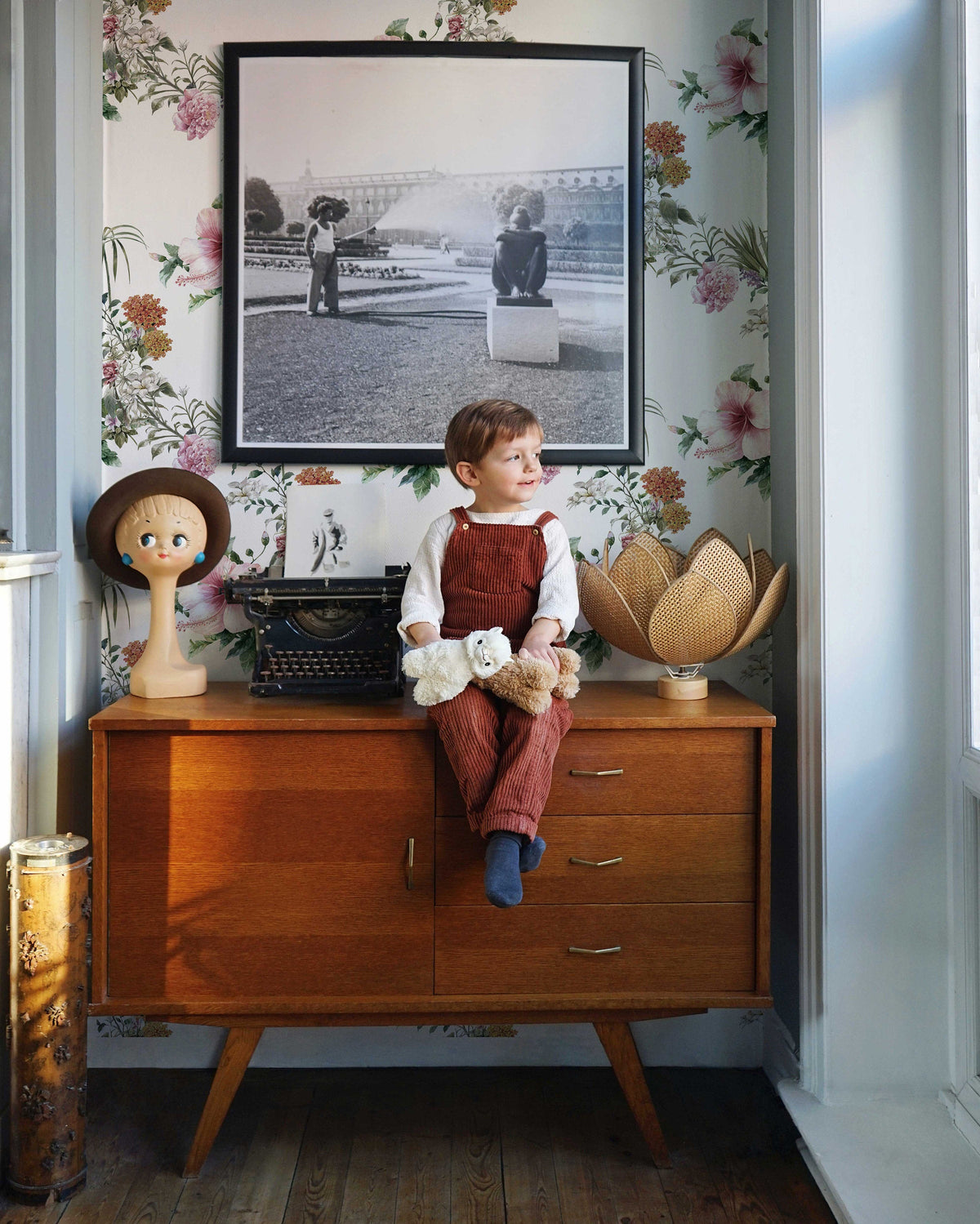 Floral wallpaper styled in a children's bedroom with a wooden dresser and framed wall art