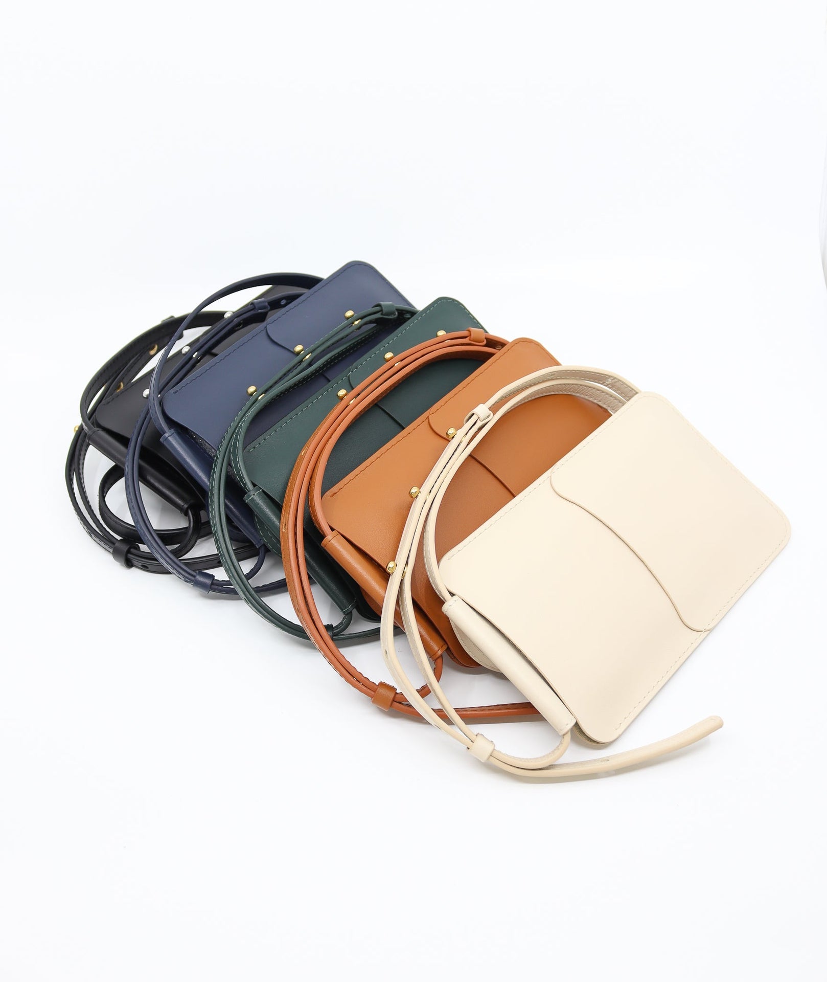 navy leather phone bag with three adjustable strap buttons and card slots shown in natural light