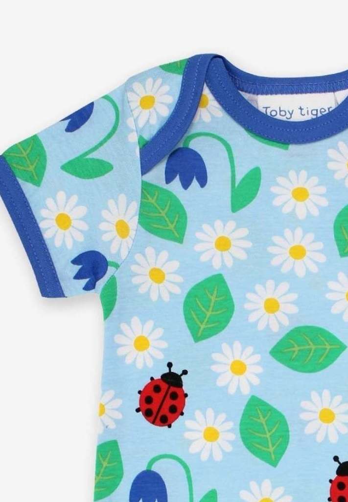 Premium baby summer romper with ladybug print in soft sky blue, certified organic cotton, short legs, snap buttons, breathable by Toby Tiger at brixbailey.com