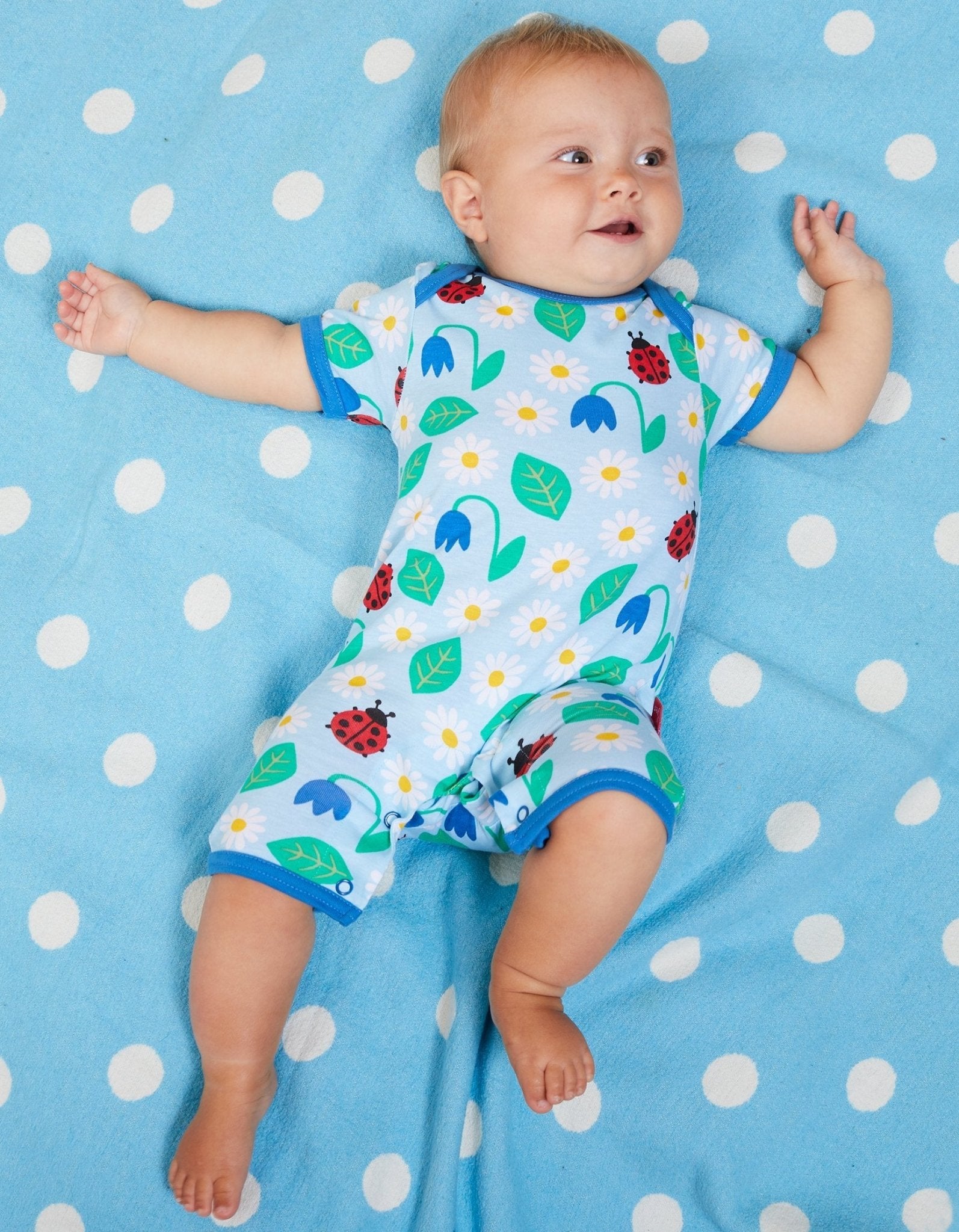 Premium baby summer romper with ladybug print in soft blue, certified organic cotton, short legs, snap buttons by Toby Tiger at brixbailey.com