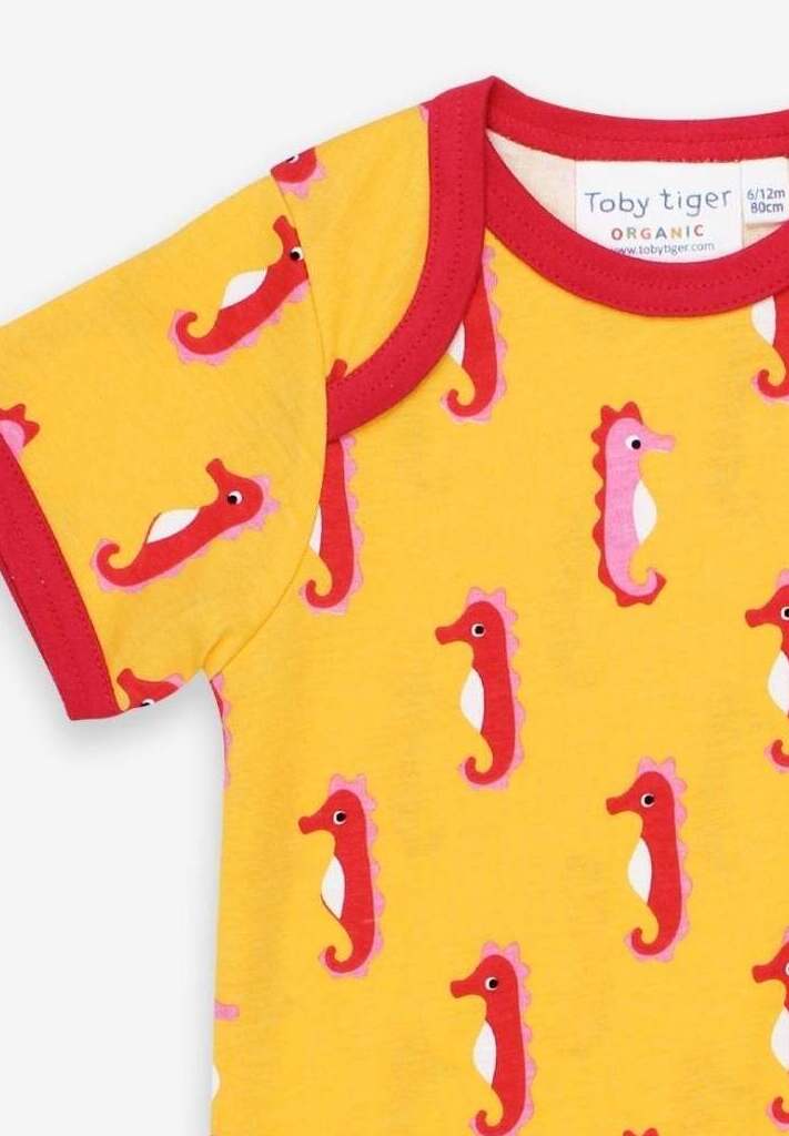 Luxury baby romper with short legs, playful seahorse design, red trim, snap buttons, organic cotton, sustainable fashion by Toby Tiger at brixbailey.com