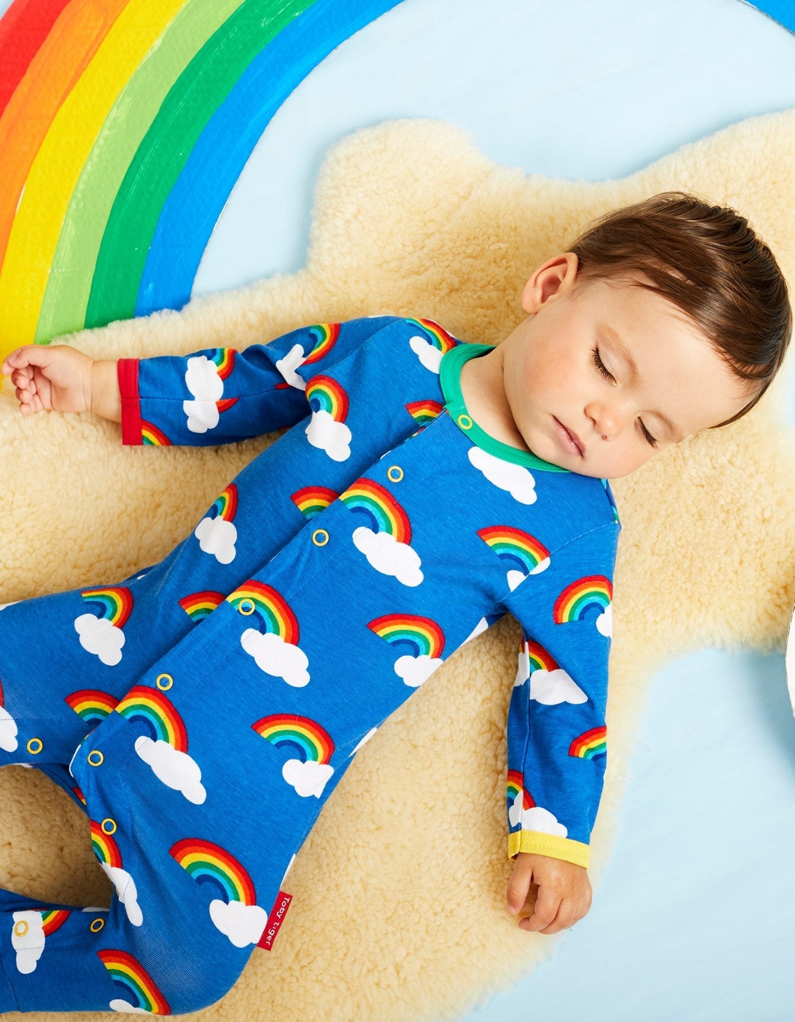 Rainbow Print Organic Cotton Baby Sleepsuit with Feet and Snap Buttons for Easy Diaper Changes by Toby Tiger at brixbailey.com