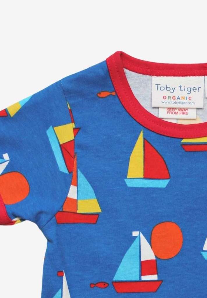 Premium organic cotton kids summer T-shirt with sailboat print, stylish red trim, deep blue background, playful fish details, GOTS certified, easy snap neck by Toby Tiger at brixbailey.com